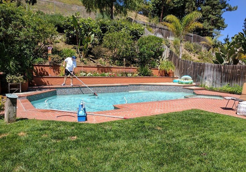 Technician cleaning a backyard pool